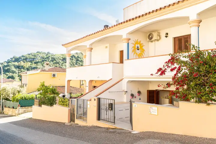 Palazzina chiara con bouganville e colline sullo sfondo